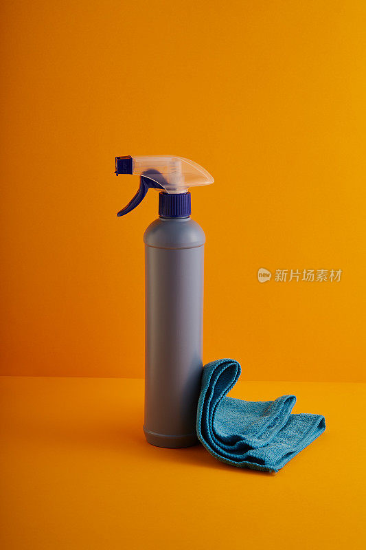 喷上清洁产品瓶和清洁布，以黄色/橙色为背景